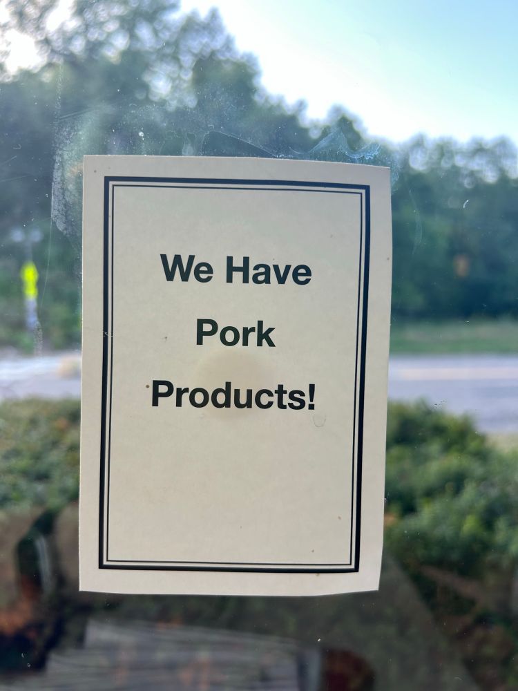 A sign on a window that states”we have pork products!”