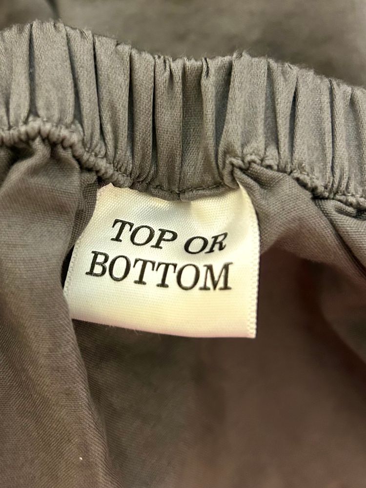 A grey bedsheet with a white tag that reads, “top or bottom”.