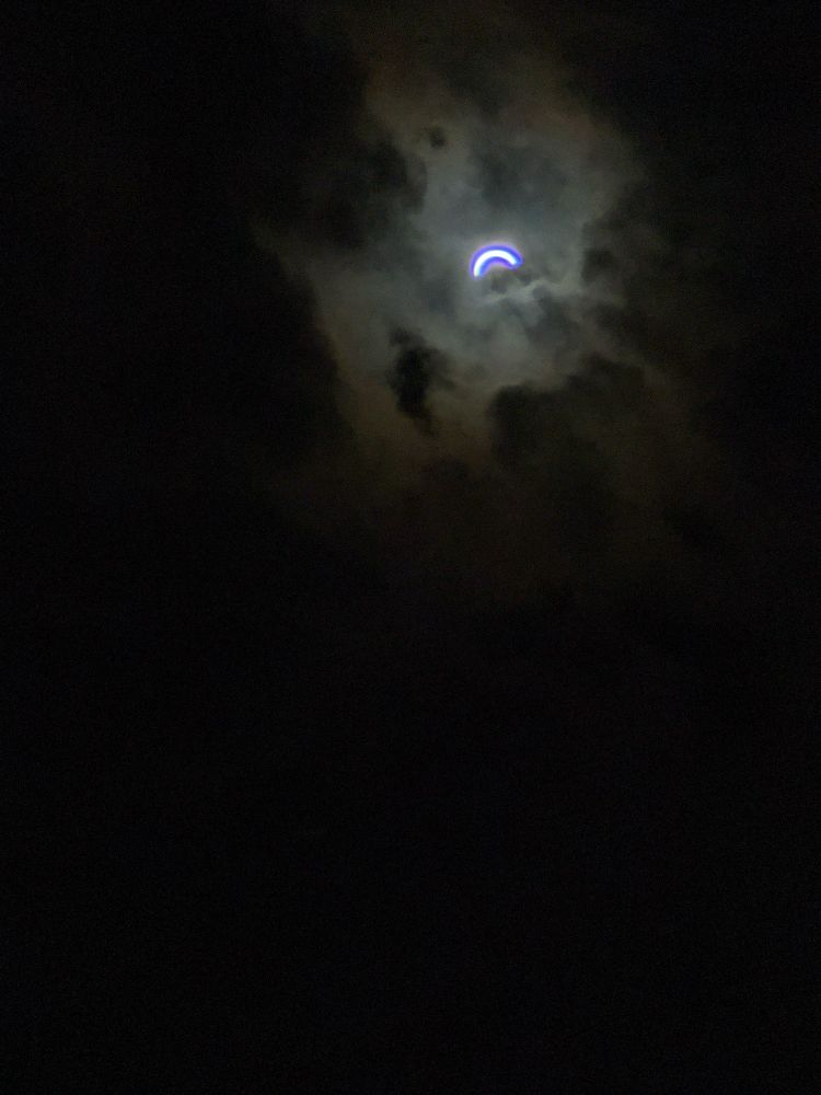 A very small sliver of a crescent just before totality. The sky is very dark