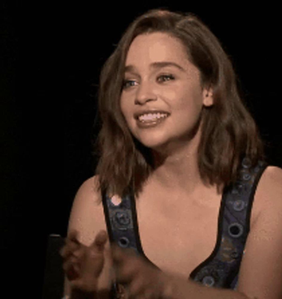 a woman in a blue and black dress is smiling and clapping .