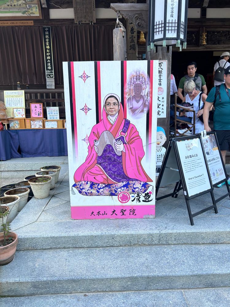 Sasha in a face cut out poster of a monk
