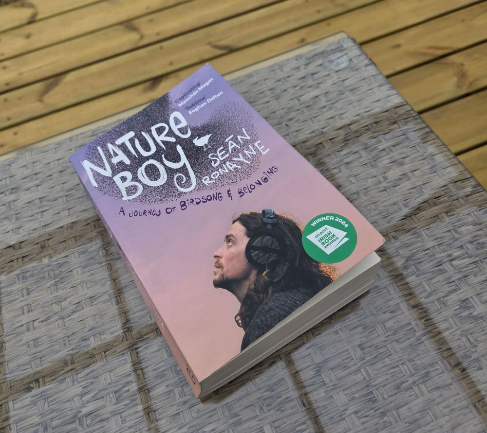 An image of the book, "Nature Boy" by Seán Ronayne, on a coffee table outdoors on a deck. 