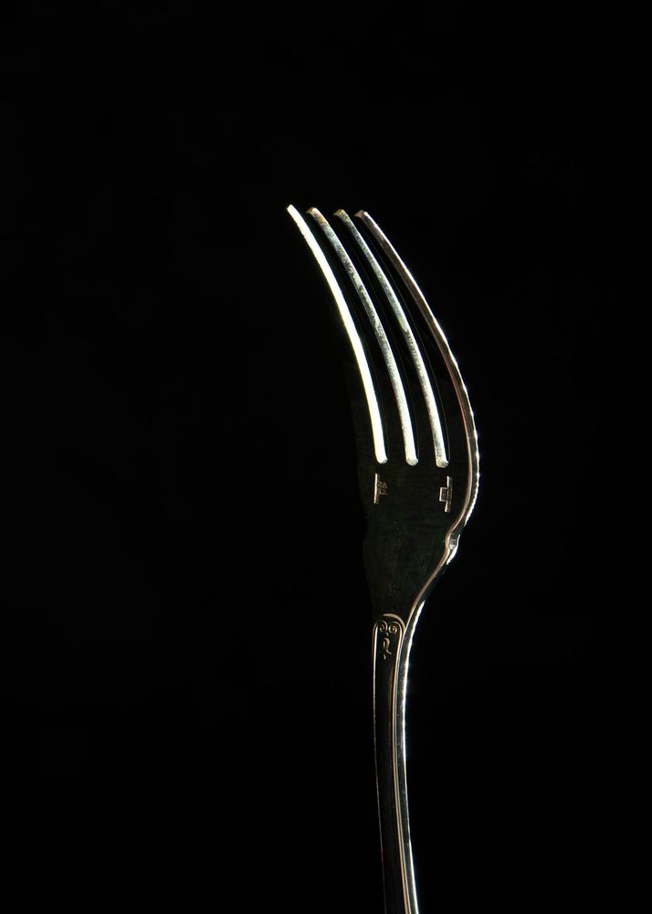 A silver fork on a black background.