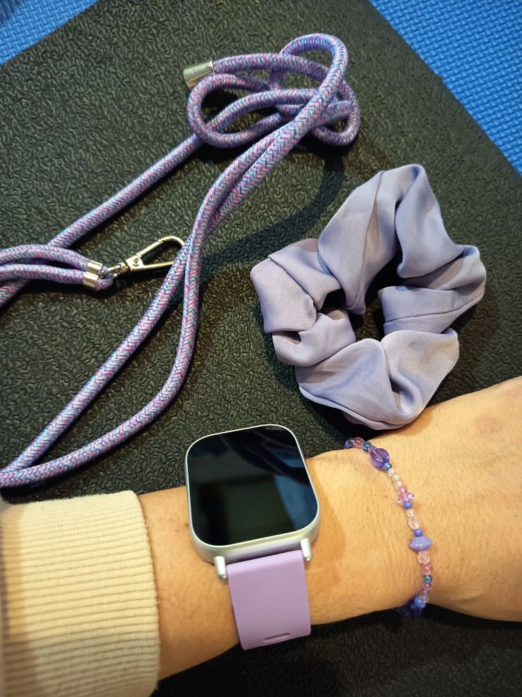 Tout est lilas, sur fond noir : bracelet de perles, bracelet de montre, chouchou et ficelle de telephone en coton tressé.