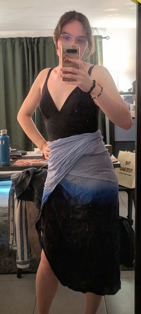 Mirror selfie in which i'm wearing a black one piece swimsuit and a blue-to-black gradient pareo