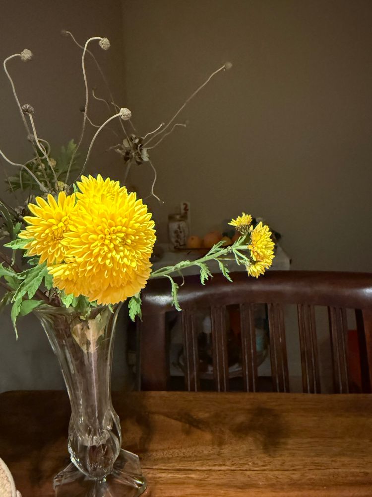 Close-up van enkele gele chrysanten in een glazen vaas 