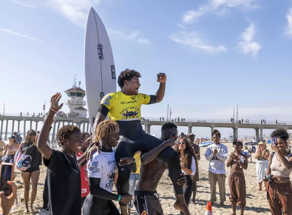 “Sidy Camara, of Senegal, celebrates winning first place in the men’s shortboard final.”

Young men carry one man on their shoulders as the crowd cheers them on. 