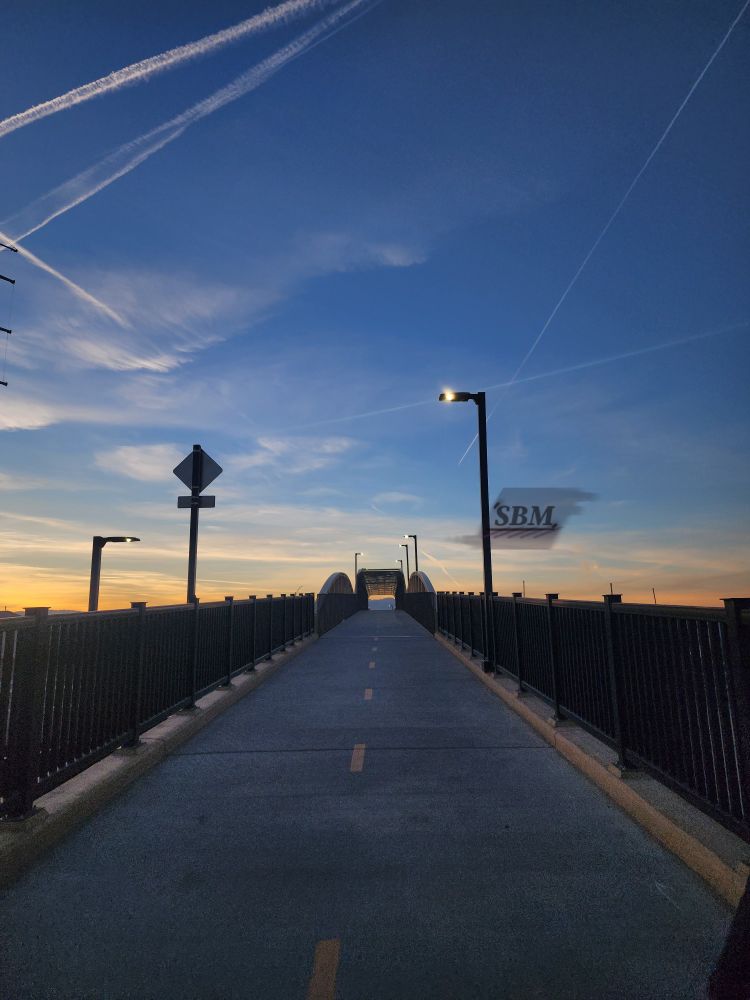 A gentle sunset of yellow and blue with jet trails and cirrostratus and stratus clouds