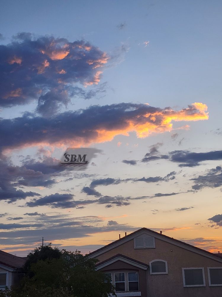 A pale blue and gold sunset creating half-illuminated blue grey and peach stratocumulus clouds