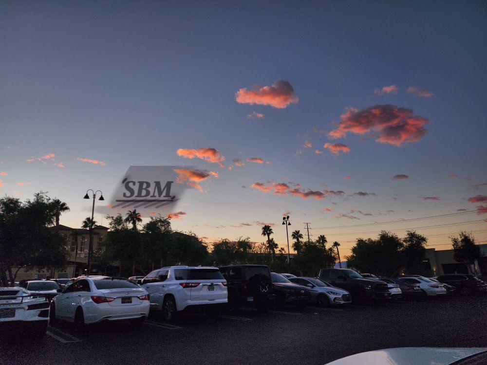 Illuminated coral pink cumulus clouds over a pale blue and light indigo sunset