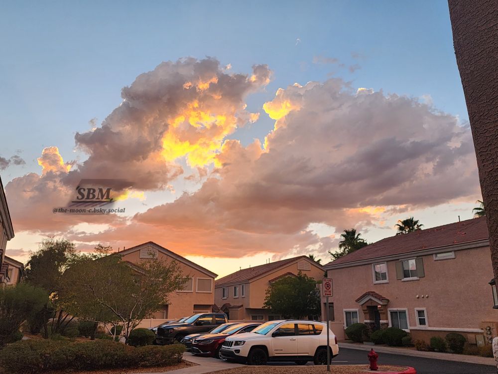 Heavenly sunlit illuminated cumulus clouds of gold, peach, and white before a light blue sunset