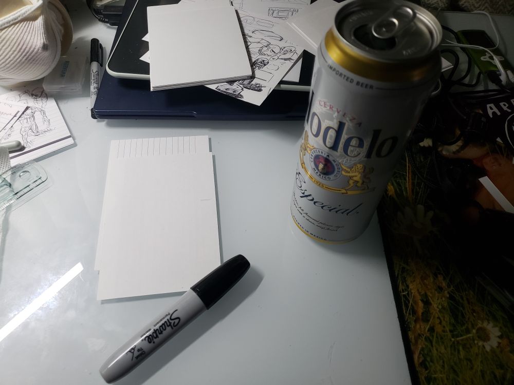 A tall can of Modelo Especial, a sharpie, and some dollar store cue cards on a desk