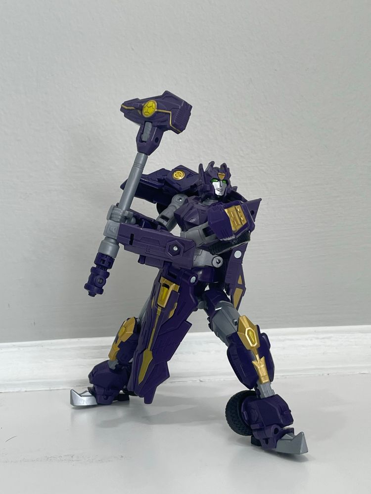Solus prime, a purple gold female robot holding a hammer 
