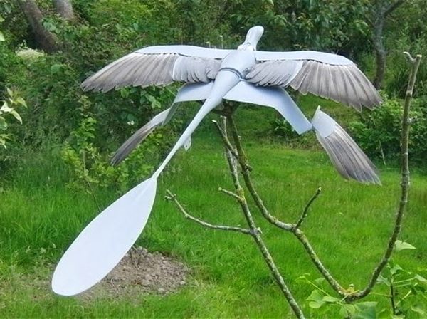 Model of Microraptor, posed in a green garden.