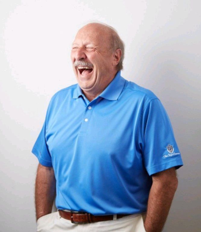 Norm Hitzges wearing a blue polo and laughing.
