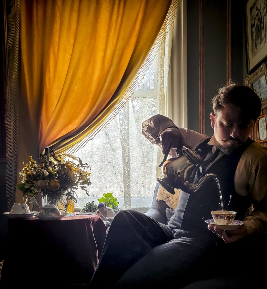 Sitting at a small table by a window, there's a bouquet of flowers that have dried in their glass vase. A couple of teacups sit on the table in front of the flowers with their cups overturned on the saucers. No friends are visiting to join for the morning tea. I sit in at the table, pouring myself some tea with turning away from the diffused light filtering through the lace curtains. My apartment is an oasis of civilization while I'm in exile. All dressed up and with nowhere to go. I'm not wearing my jacket, but still wearing my best antique suit.