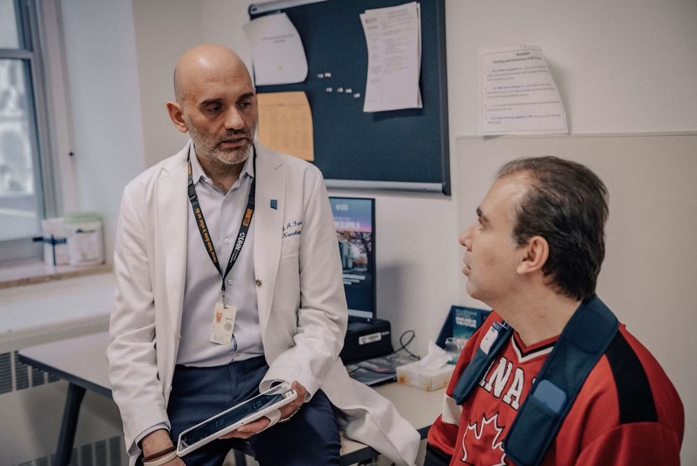 Dr. Alfonso Fasano, a neurologist at University Health Network in Toronto, talks with Dwyer. (Turgut Yeter/CBC)