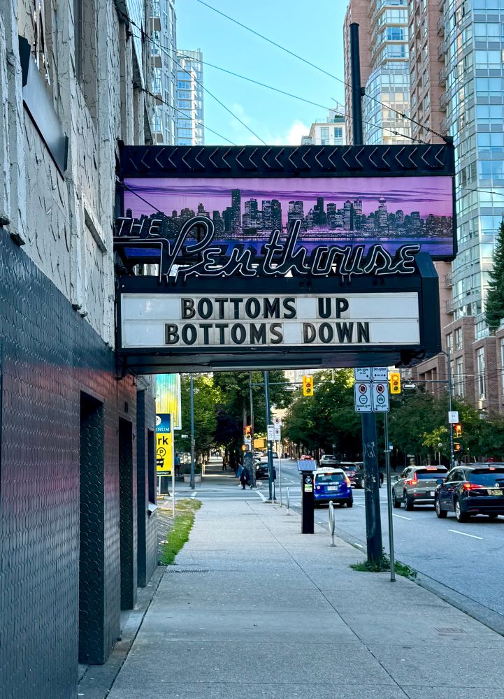 The marquee of a gentlemen’s club, The Penthouse, with the lettering Bottoms up, Bottoms Down, presumably to commemorate pride weekend in Vancouver. 