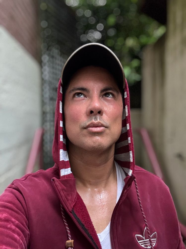 A selfie of a sweat soaked middle aged man. The hood of his sweater is pulled up and he looks skyward defiantly.