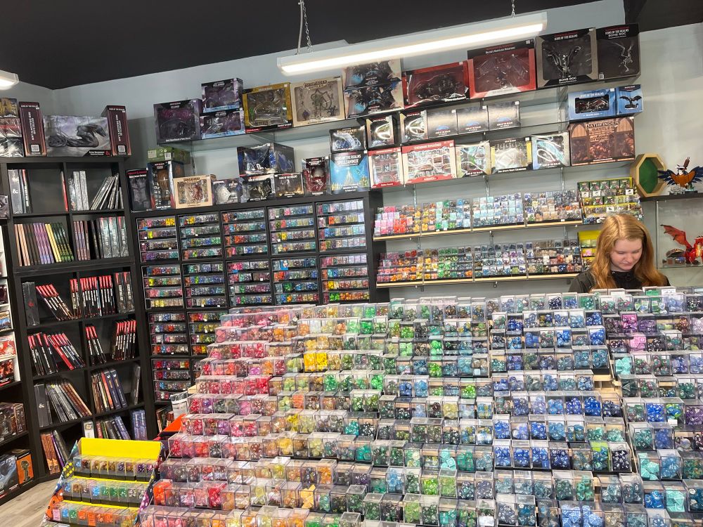 Shot of game store merch collection. Dice, books, collectibles, minis, boardgames. 