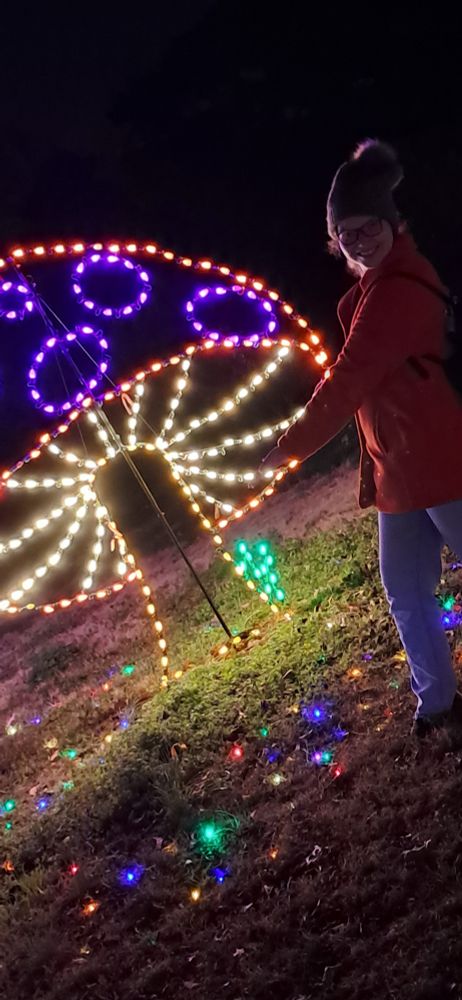 Me (Amanda) gesturing towards a multicolored Christmas light mushroom 