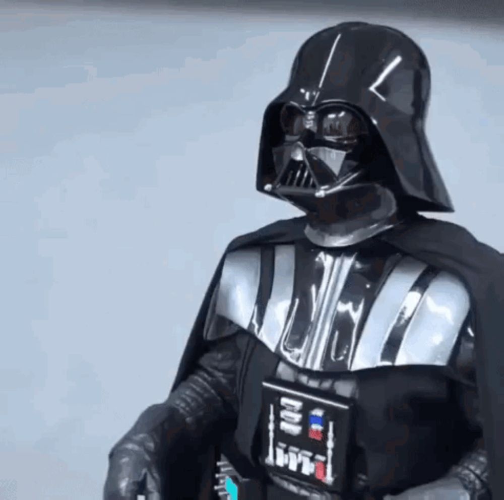 a person in a darth vader costume is standing in front of a white wall .