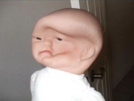 a baby doll head someone stepped on, the face is compressed inside