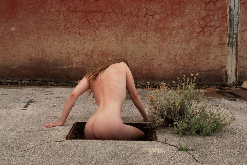 Nude emerging from underground on a derelict place.
