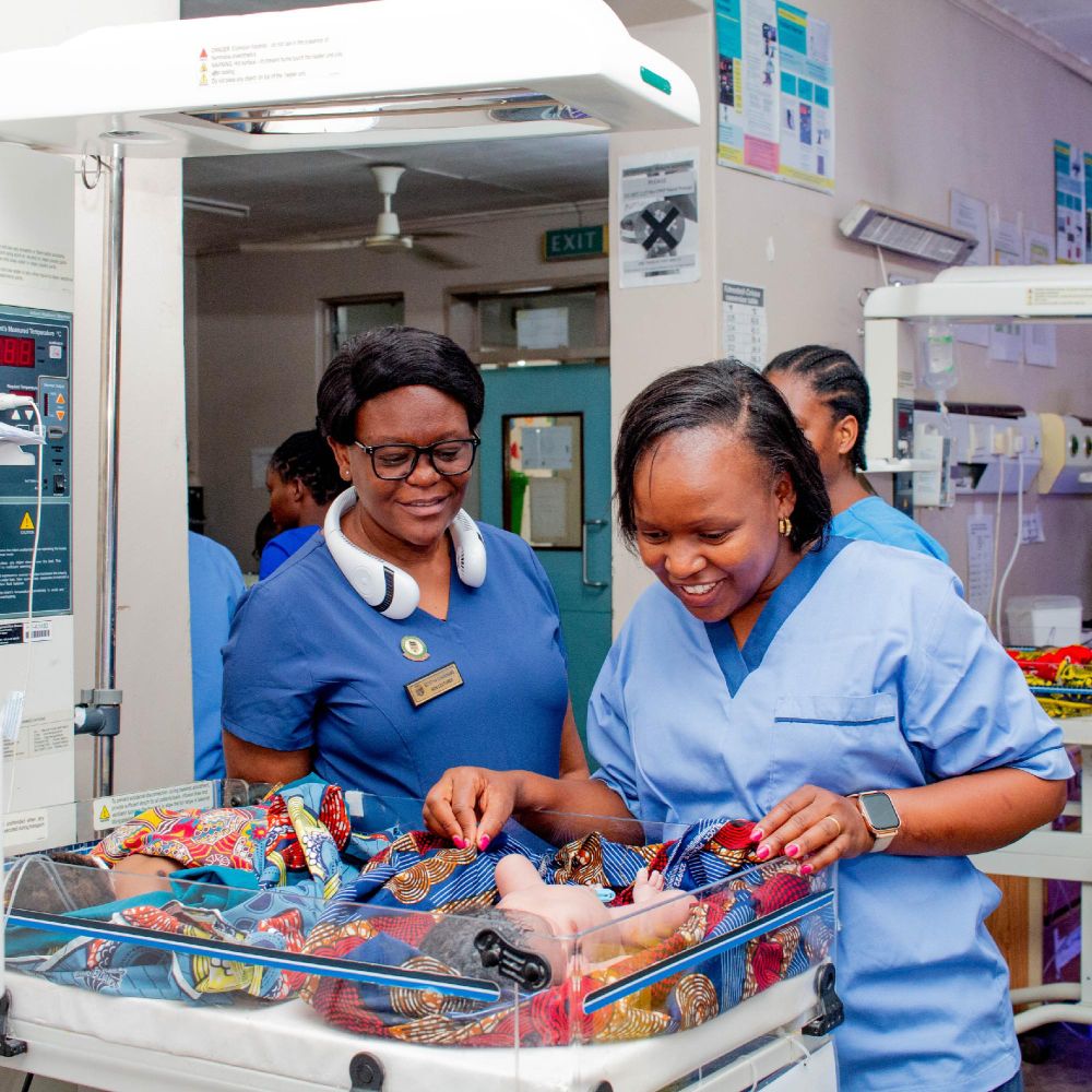 Two maternal nurses checking in on newborn baby