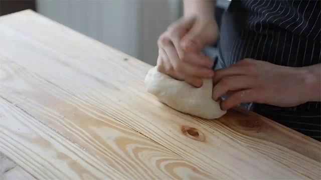 a person is rolling dough on a wooden table