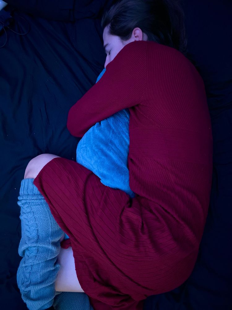 Lily curled up in a red dress and leg warmers cuddling a shark stuffie