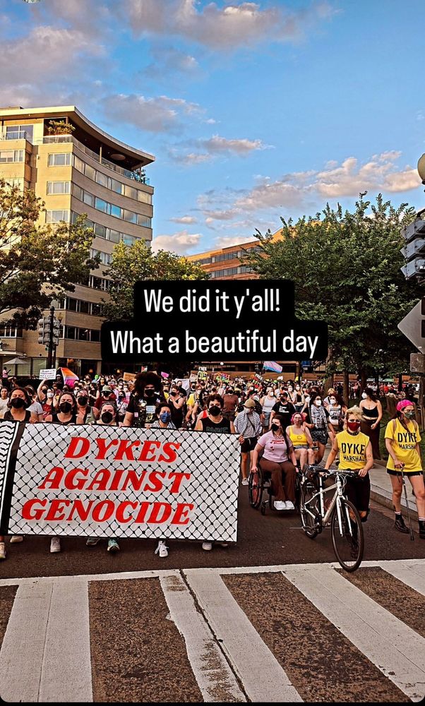 A photo of the 2024 Washington DC dyke March. Hundreds of dykes fill the street with 100% masking. They hold a sign that says “dykes against genocide”. A caption reads “we did it y’all! What a beautiful day”