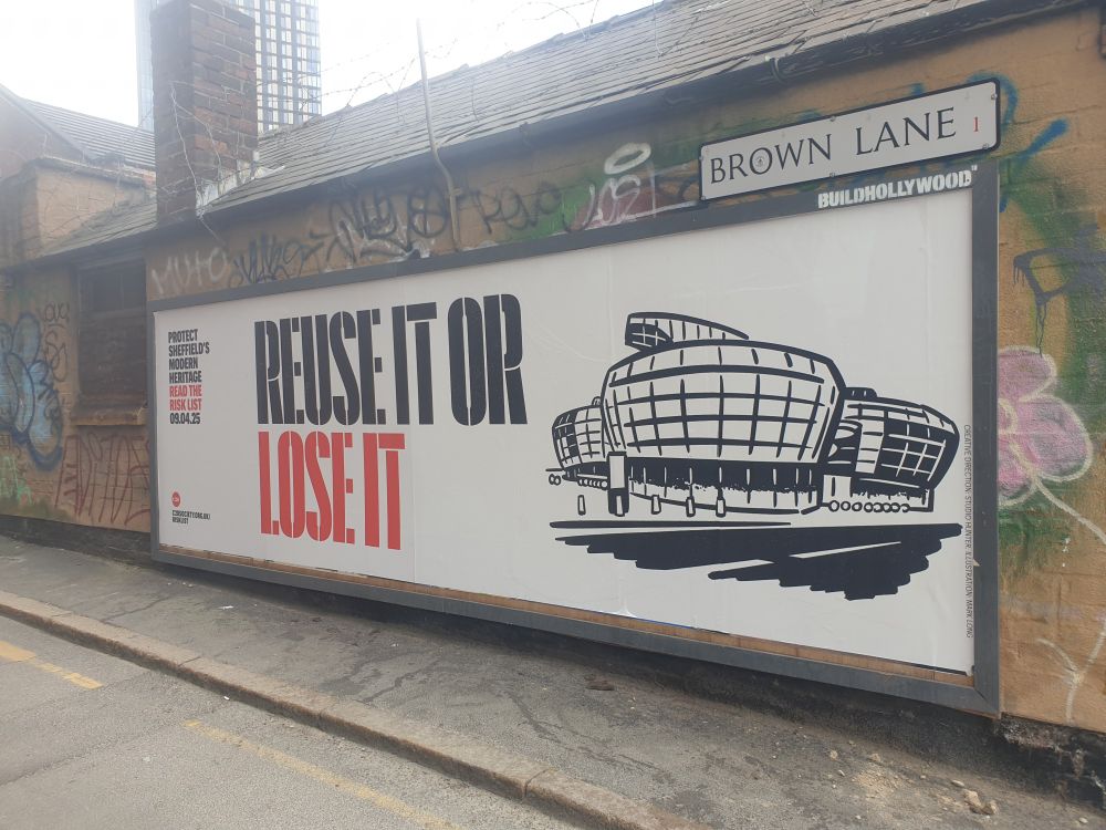 Long billboard poster that reads "reuse it or lose it" from the 20th century society campaign to protect the metal kettle shaped building that currently houses Hallam students union