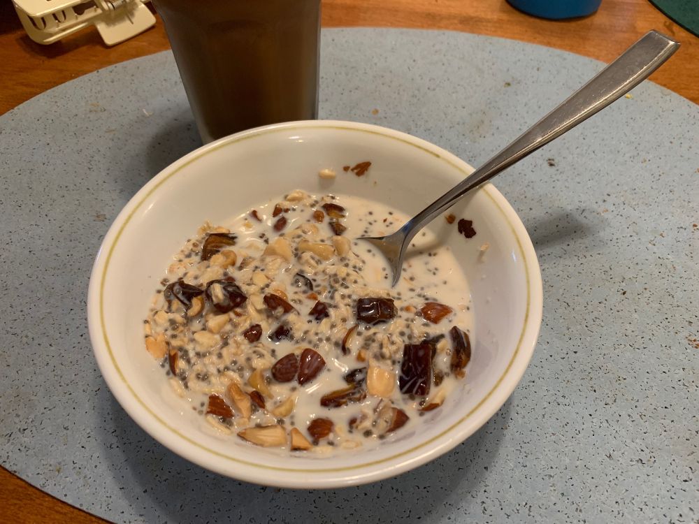A bowl of overnight oats served with chopped mixed nuts, dates, and chia seeds