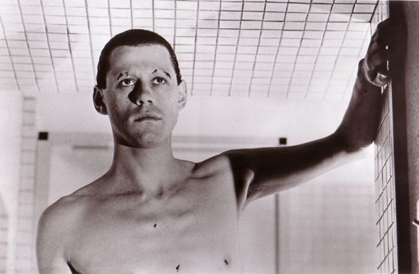 Bob Geldof from "The Wall." Torso-and-up shot, without a shirt, with shaved eyebrows, looking like a psycho.