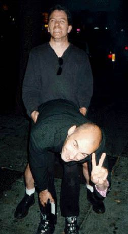 Me, behind Grant Morrison, doggie style, Grant bent over, smiling, flashing a peace sign.