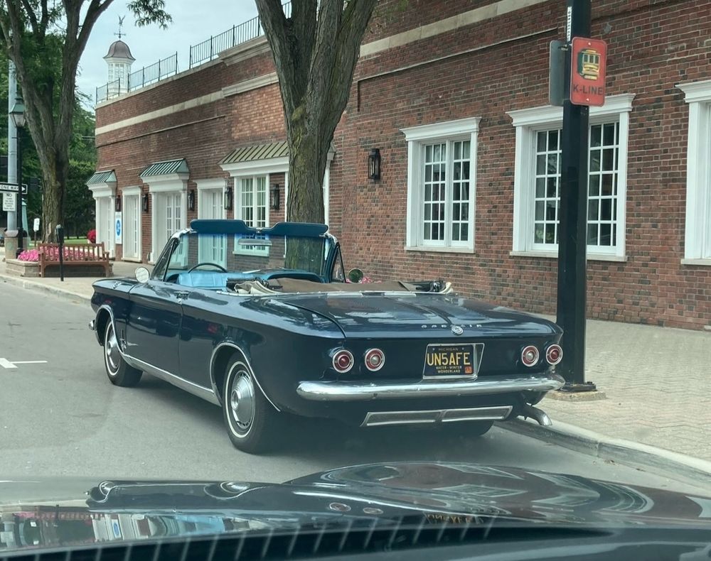 A rear view of a Chevrolet Corvair automobile with the license plate “UNSAFE”