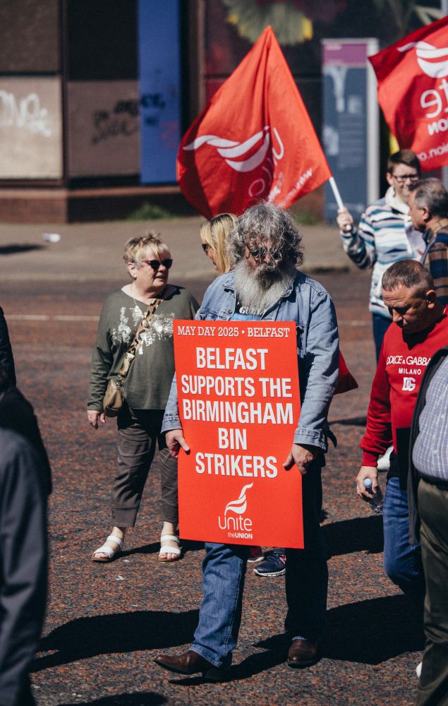 A man holds a placard reading "Belfast supports the Birmingham Bin Strikers"