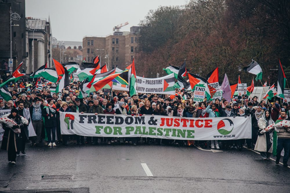 January 2024 National Demonstration in Dublin for Palestine. Photo of a crowd of thousands with Palestinian flags waving and "Freedom & Justice for Palestine" on the banner held at the front of the march.