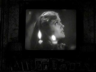 Still image. A projection of Gloria Swanson in  the film 'Queen Kelly' by Erich von Stroheim where she is lit by two candles.