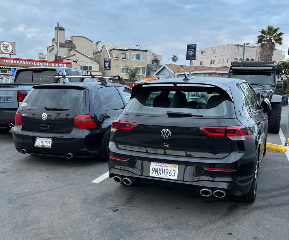 A black VW R32 and a black VW Golf R next to each other in a parking lot