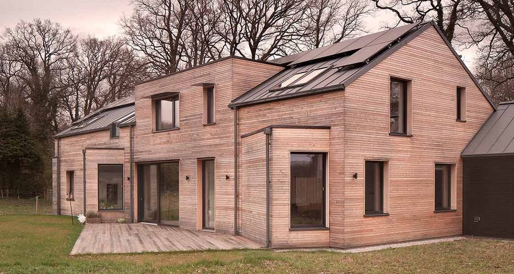 Picture shows a timber frame passive house, set on a green lawn