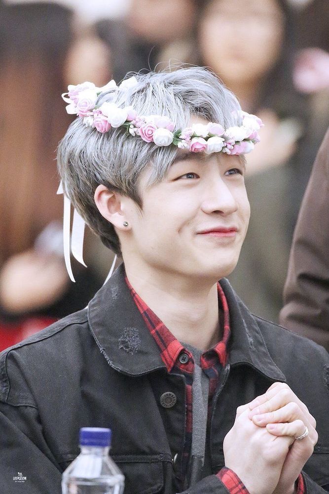 bang chan with a flower crown askew on his  head, smiling up at someone with dimples out