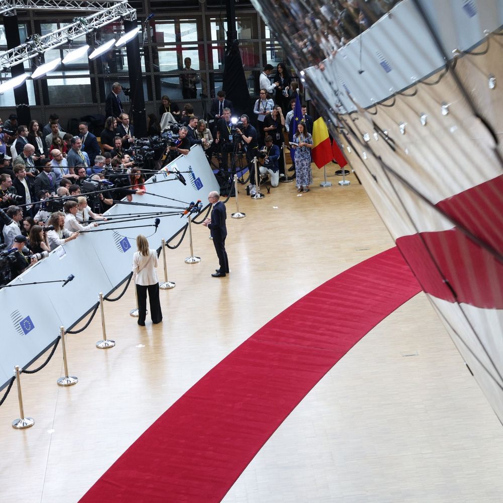 On the right you see a red carpet and on the left people talking in front of a set of microphones (to journalists). The red carpet reflects on a mirror on the right. 