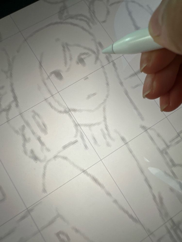 Jocelyn’s hand is holding the Apple Pencil, hovering over. they’re showing the draft art of Jacqueline from Corrupted Memories on their Procreate IPad screen.