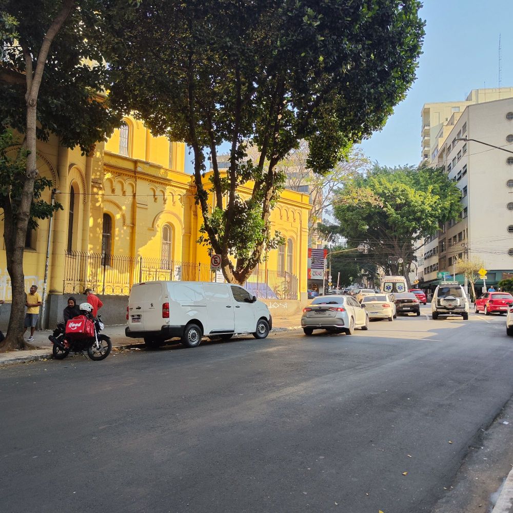 foto de longe, a fim de identificar a arvre infame: na lateral direita da igreja da Santa Cecília (que fica na pracinha de acesso ao metrô). foto em dia ensolarado, a parede amarela da igreja e alguns carros, a insuspeita árvore ali plena como as outras.