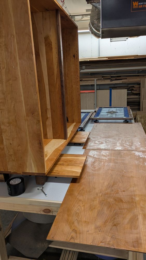 Picture of stained glass framed in a walnut door with a cherry cabinet in the background 