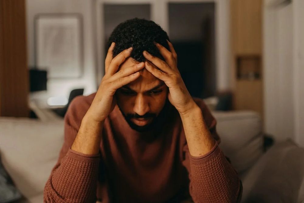 A man holding his head in his hands, looking upset and despondent. 