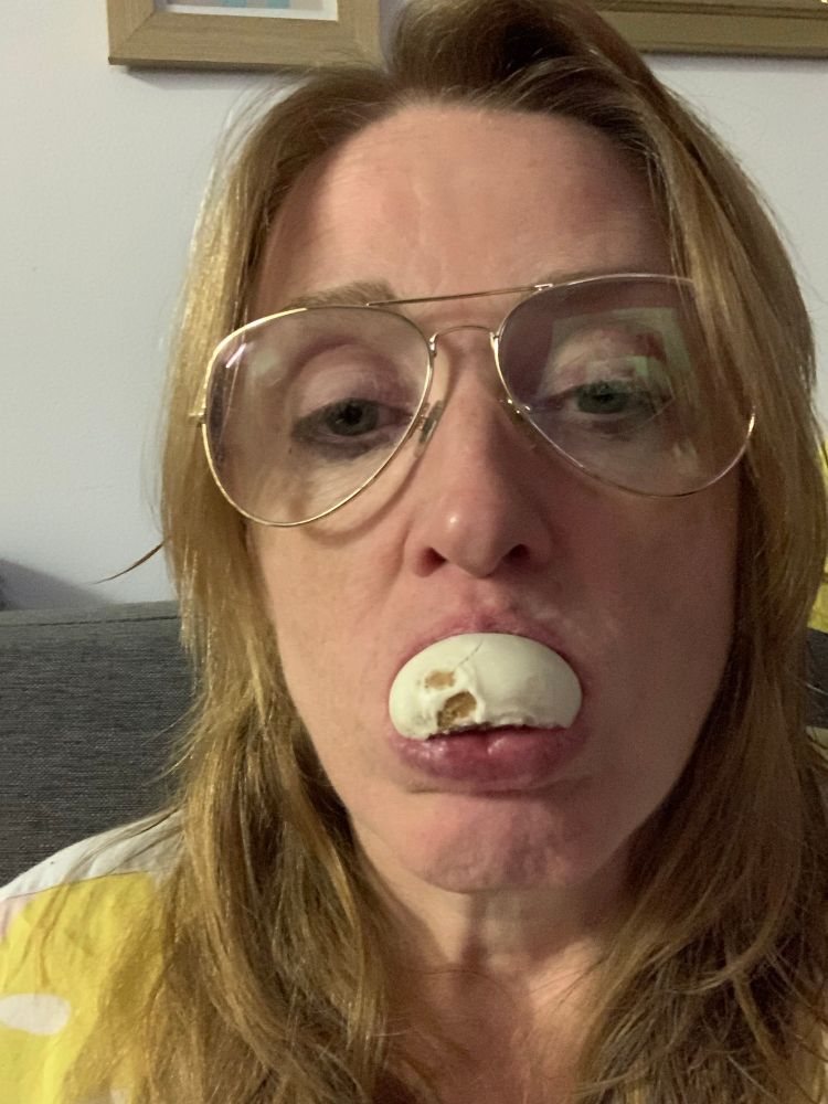 A tired 49 year old woman with her hair washed and a clean face wearing her prescription glasses and munching on a pfeffernüsse post-show.