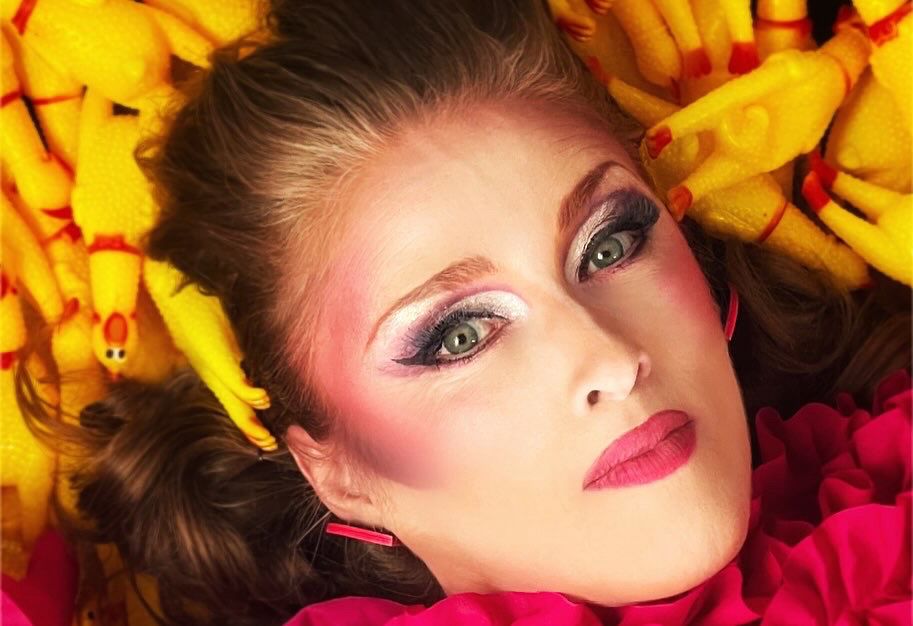 Glamorous woman gazing at camera lying in a pile of small rubber chickens